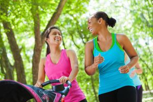 Happy women walking together in park with baby strollers