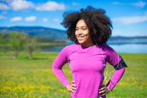 Woman relaxing from exercising in nature, wearing smart technology