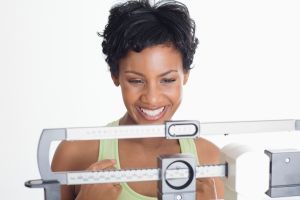 Close up of an African American Woman on a scale and looking happy.