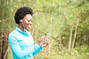 One African descent woman exercising, using cell phone in neighborhood park.