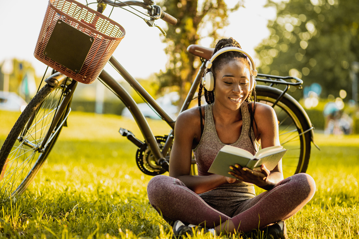 Young African American woman is reading a book in nature